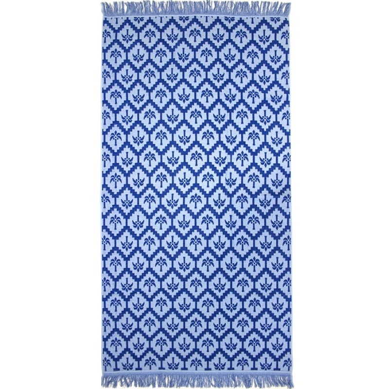 alt="Cobalt blue beach towel designed with palm tree pattern and tassels on both ends"