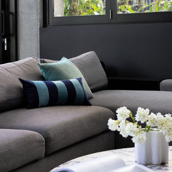 Bambury Cooper Ocean Cushion styled on a grey sofa with coordinating accents

