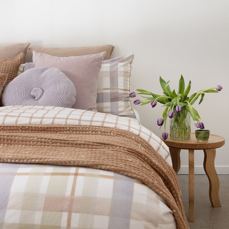 alt="Close-up view of a digitally printed hand-painted watercolour check pattern in sage green, lilac ash, and tan on a crisp white base quilt cover set in a cosy bedroom"