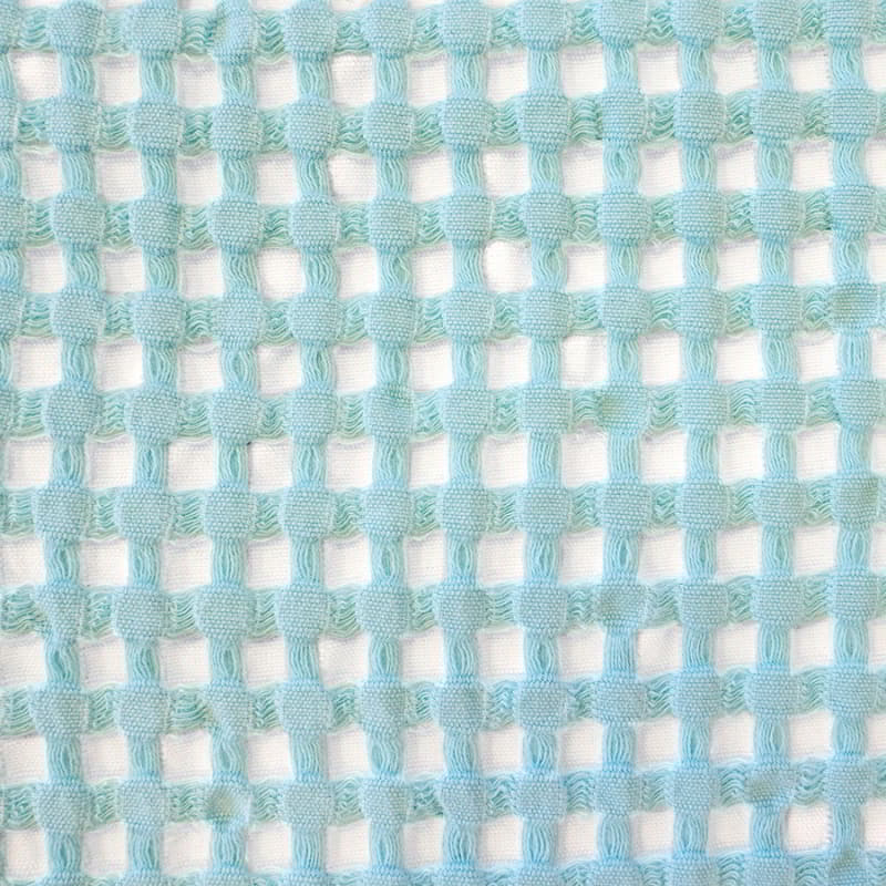 Close-up image of a blue and white fabric, emphasizing the exquisite texture of the reversible Dora Aqua Throw.