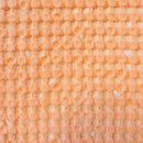 A vibrant peach cushion with a two-tone waffle texture and small squares, perfect for enhancing your living space's aesthetic.
