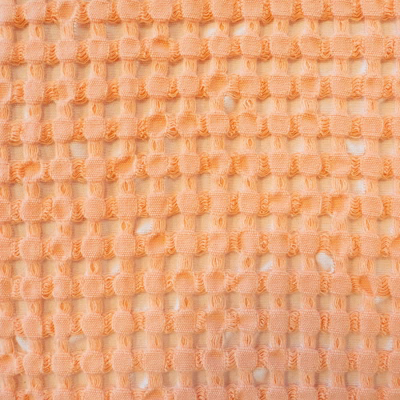 A vibrant peach cushion with a two-tone waffle texture and small squares, perfect for enhancing your living space's aesthetic.