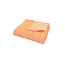 A cosy folded Dora Peach Throw, perfect for adding warmth and style to any living space.