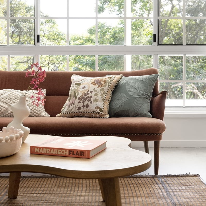 alt="Green velvet cushion designed with eucalyptus leaves in a modern-theme living space"