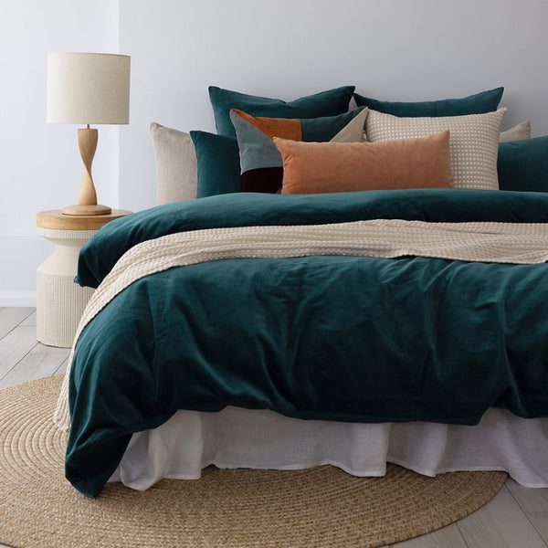 Sumptuous cotton velvet quilt cover set in deep teal on a cosy bed.