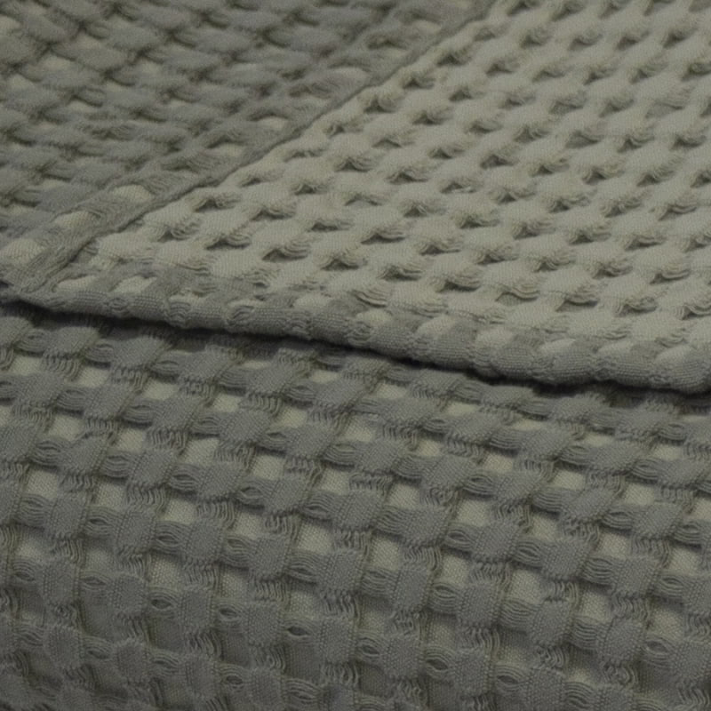 alt="Close-up view of a two-toned sage green throw with a beautiful waffle texture"