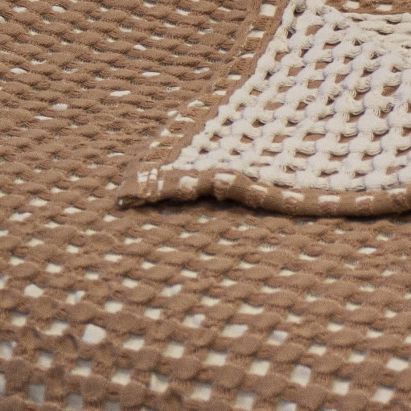 alt="Close-up view of a two-toned brown throw with a beautiful waffle texture"