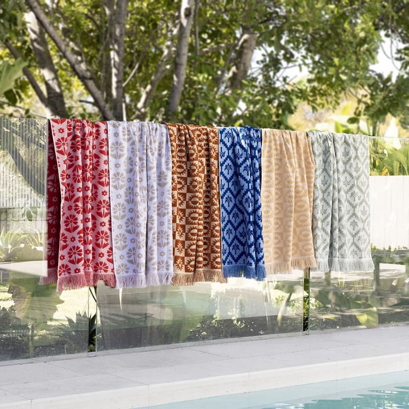 alt="Various colours and designs of beach towels hanging beside the pool"