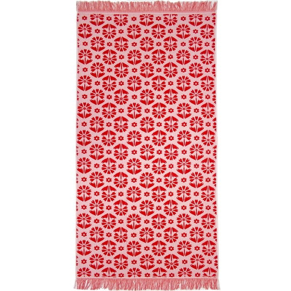 alt="Red beach towel designed with floral pattern and tassels on both ends"