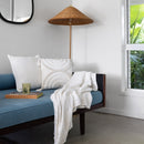 alt="Striped white and natural throw with fringe at both ends placed on a sofa in modern-theme living space"