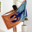 A woman shows off a colourful lobster beach towel, blending luxury and functionality for a chic day at the beach or pool.