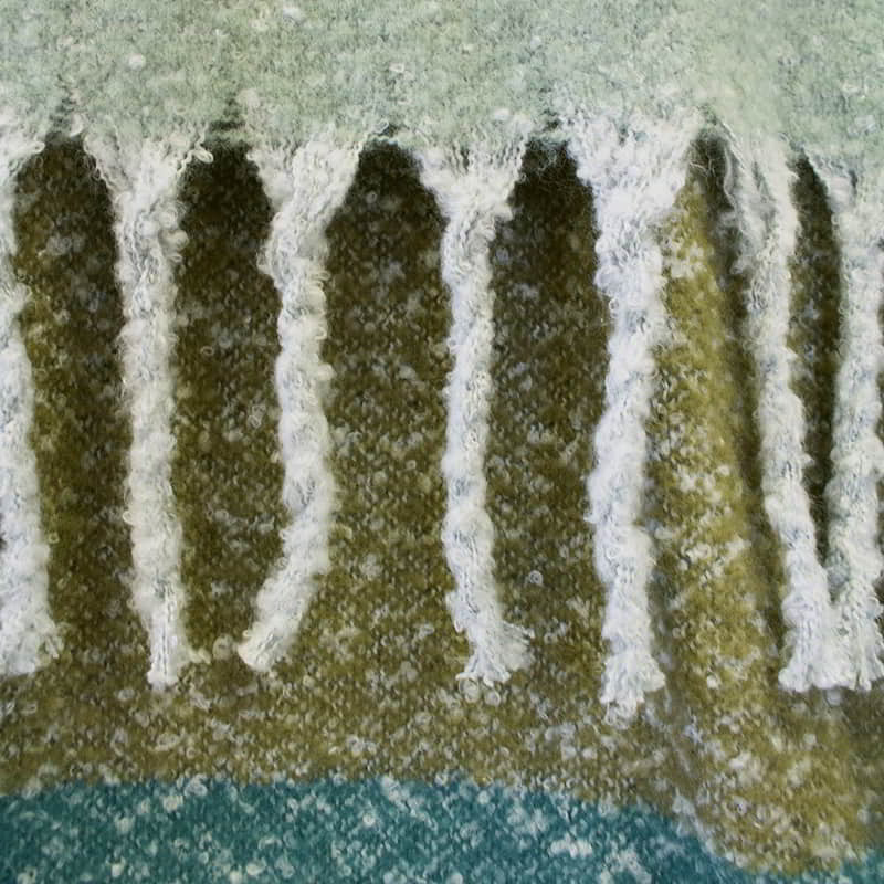 Detailed view of a shade of grreen throw with fringes, beautiful colours in large check pattern, extra-long with tassels, soft like mohair, machine washable.