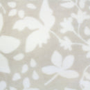 Detailed shot of luxurious natural blanket with a two-tone floral pattern, super soft and silky fabric, perfect for adding warmth to the bed. Machine washable.