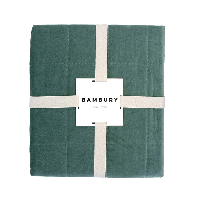 Packaging details of a luxurious green throw crafted from sumptuous cotton velvet with a quilted square pattern for added elegance.