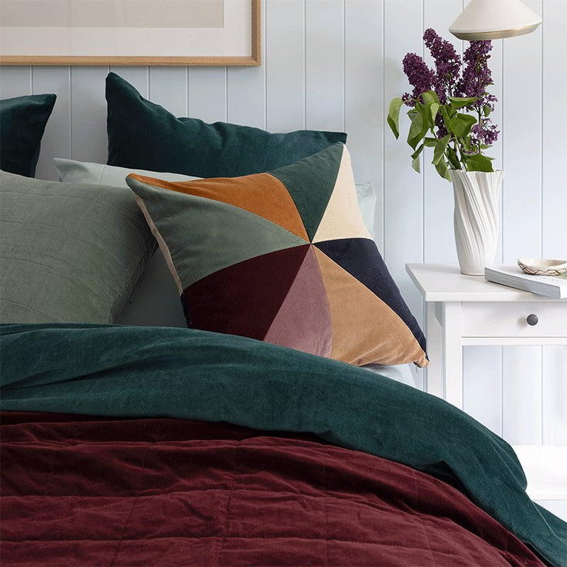 Sumptuous cotton velvet throw on a bed with quilted square pattern, long length, and coordinating cushion available.