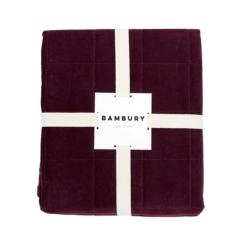 Packaging details of a luxurious maroon throw crafted from sumptuous cotton velvet with a quilted square pattern for added elegance.