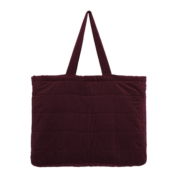A large burgundy tote bag made from sumptuous cotton velvet featuring a quilted square pattern, cotton lining, and a pocket.
