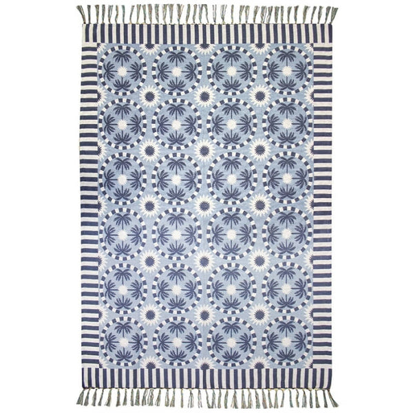 alt="A light blue and dark blue blanket designed with palm tree pattern and tassels on both ends"
