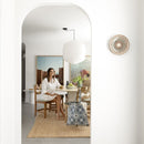 alt="A woman sitting in the dining area with a light blue and dark blue tote bag designed with a palm tree pattern, placed on the floor"