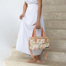 A woman holding a floral print Sadie small cooler bag, designed for stylish and practical food and drink storage on the go.