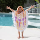 A kid in a vibrant shaped luna tree poncho stands by a pool, enjoying a sunny day and ready for fun after swimming.