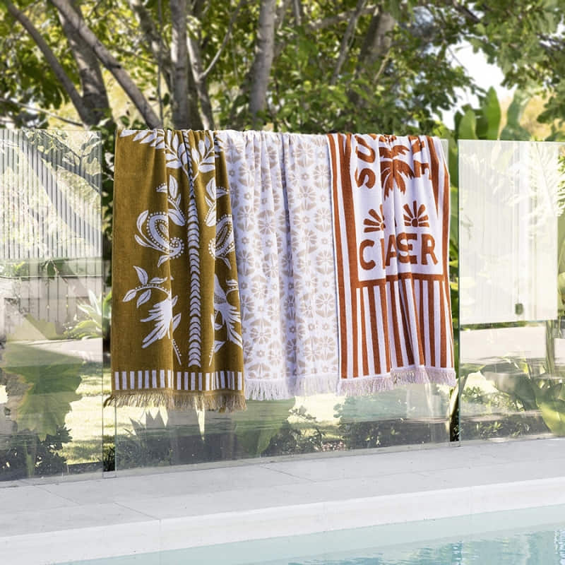alt="Various colours and designs of beach towels hanging beside the pool"