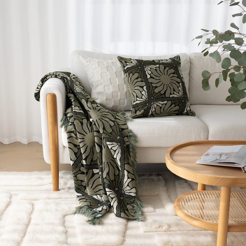 A cosy living room featuring a white couch, and a Zinnia Moss Cushion with a floral pattern.