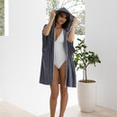 A woman in a white swimsuit, showcasing a comfortable adult poncho perfect for summer activities.