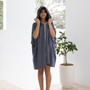 A woman wearing a navy adult poncho, perfect for summer outings by the water.