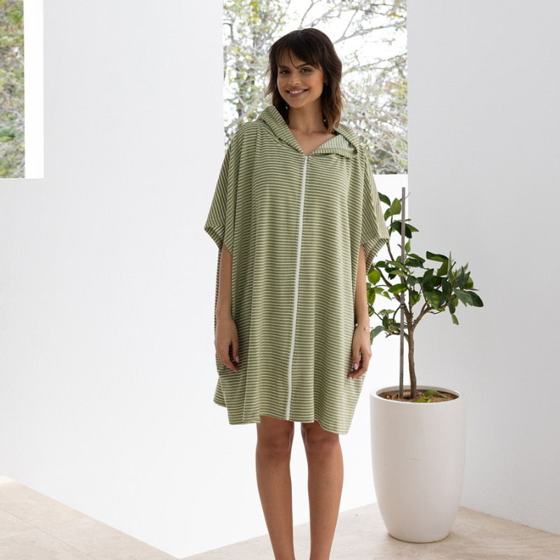 A woman wearing a green adult poncho, representing effortless style and comfort, suitable for travel.