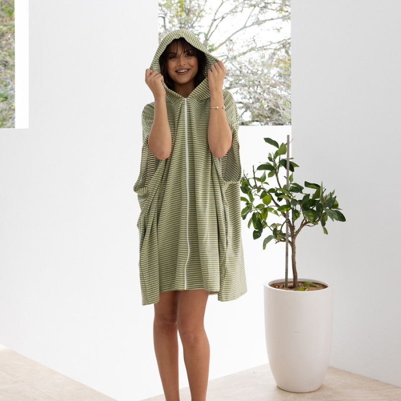 A woman in a green adult poncho, showcasing comfort and style, perfect for post-swim relaxation or travel warmth.