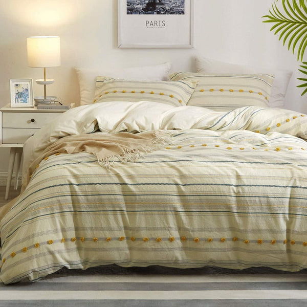 alt="An elegant quilt cover set in a yellow hue feature a delightful tufted pom poms"