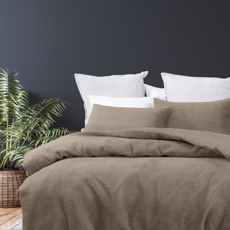 alt="A luxurious quilt cover set in a brown hue will add cosiness to your bedroom."
