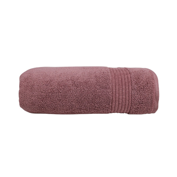 alt="A neatly rolled dusty rose valencia zero twist towel featuring its soft and intricate details."