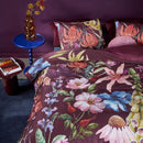 Bedding House Lily Multi quilt cover with vibrant floral print on burgundy background, styled on bed.