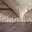 Close-up of quilt cover showing fine ethnic patterns in warm brown and cream tones