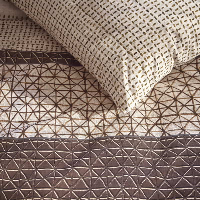 Close-up of quilt cover showing fine ethnic patterns in warm brown and cream tones