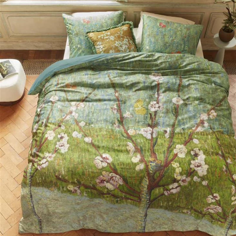 alt="Top view of a quilt cover inspired by Vincent van Gogh's 'Blossoming Peach Tree' painting in a cosy bedroom."