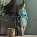 alt="A woman wearking Van Gogh-inspired Almond Blossoms kimono with turquoise-blue background"