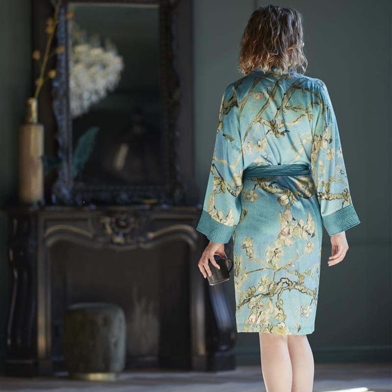 alt="A woman wearking Van Gogh-inspired Almond Blossoms kimono with turquoise-blue background"