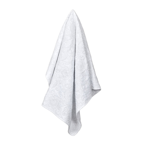 alt="A cotton throw designed with a floral embossed pattern in white and subtle greys"