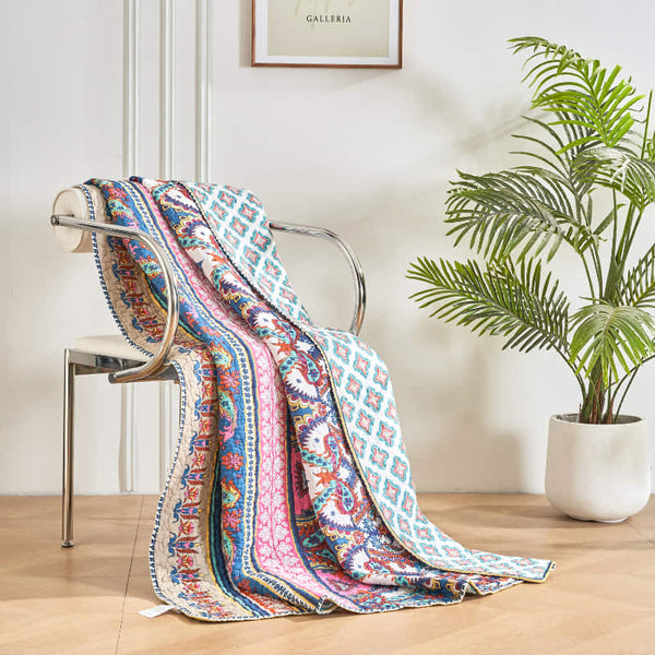 A richly detailed patterned throw in pink, blue, and yellow hues against a white background, featuring a bohemian style with intricate geometric and floral motifs.
