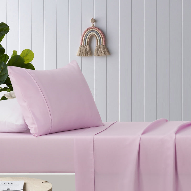 alt="A pink, plain dyed microfibre sheet set in a cosy bedroom"