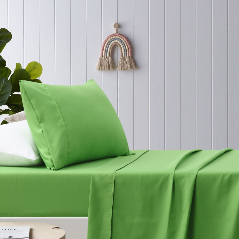 alt="A green, plain dyed microfibre sheet set in a cosy bedroom"