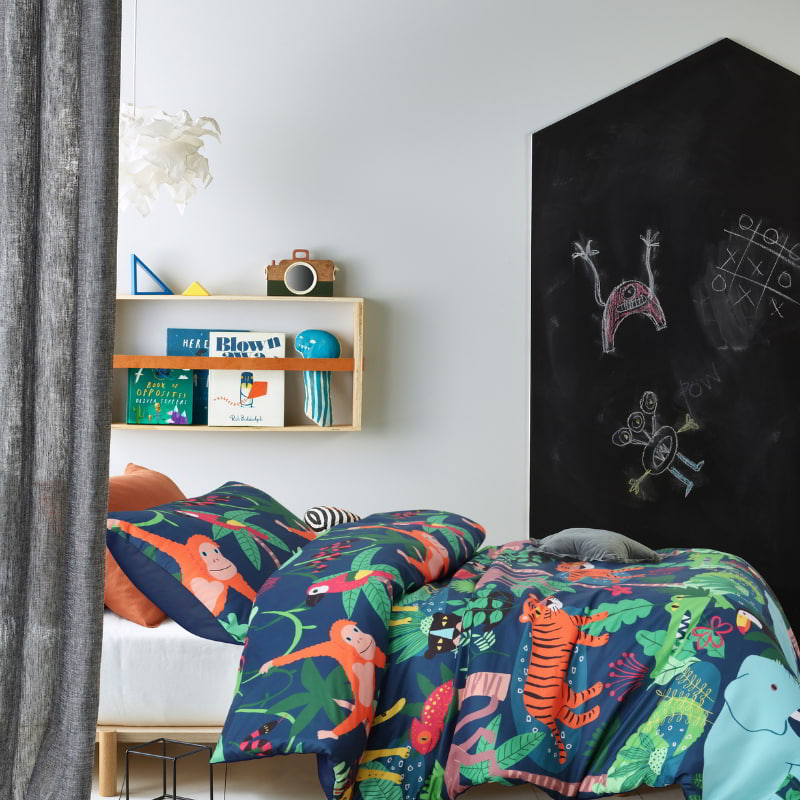 alt="Glow in the dark quilt cover set with captivating, colourful rainforest design featuring white, black, blue, red, orange, grey, yellow, and green tones in a playful bedroom"