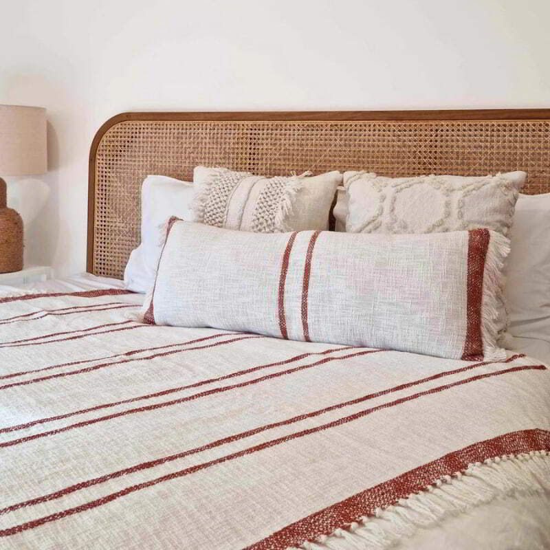 alt="Ivory and Brick Throw with tassels and subtle stripe design in a luxurious bedroom."