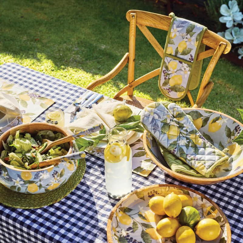 alt="overview of a table setting featuring citrus fruits and dishes  over a blue patterned tablecloth"