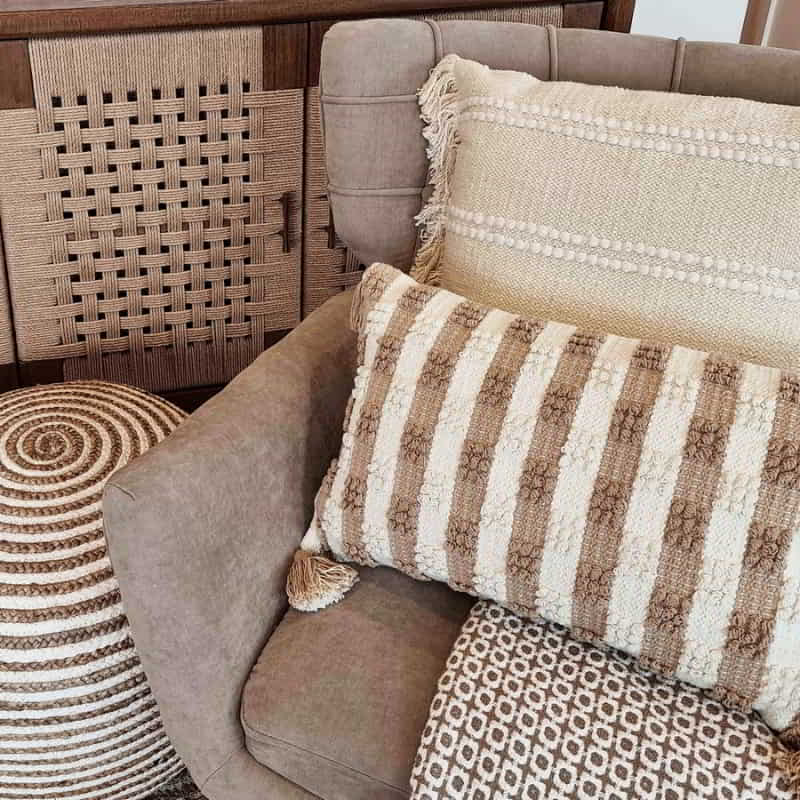 alt="A cream and white cushion featuring thin stripes design in a cosy sofa"