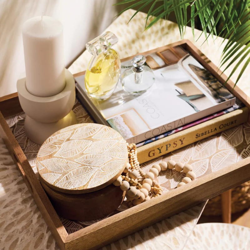 alt="A natural serving tray with stuffs featuring a handcrafted delicate leaf design from high-quality mango wood in.
