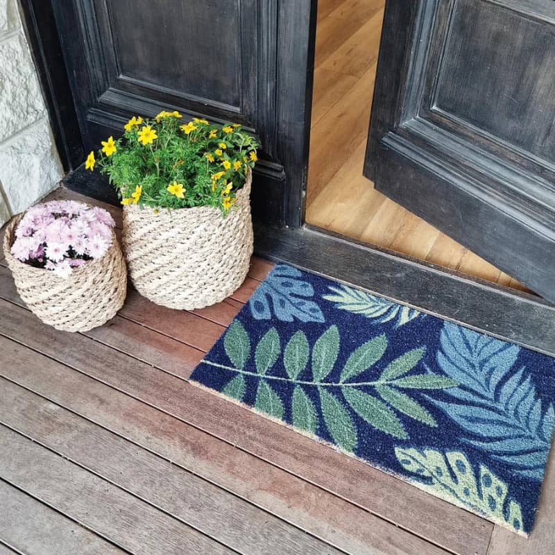 alt="A tropical leaves coir mat in front of door featuring its high quality coir materials and unique designs."